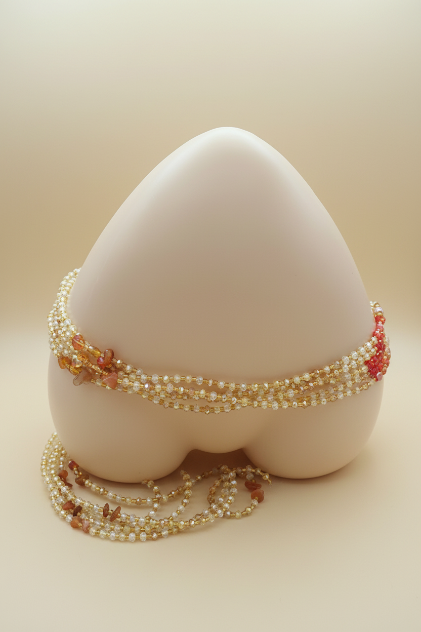 Handmade gold crystal waist beads on cream background