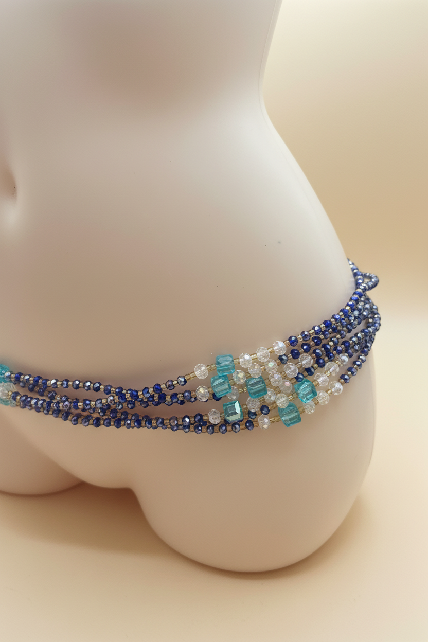 Close up of blue and teal waist beads on cream background