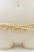 Handmade gold crystal waist beads close up on cream background
