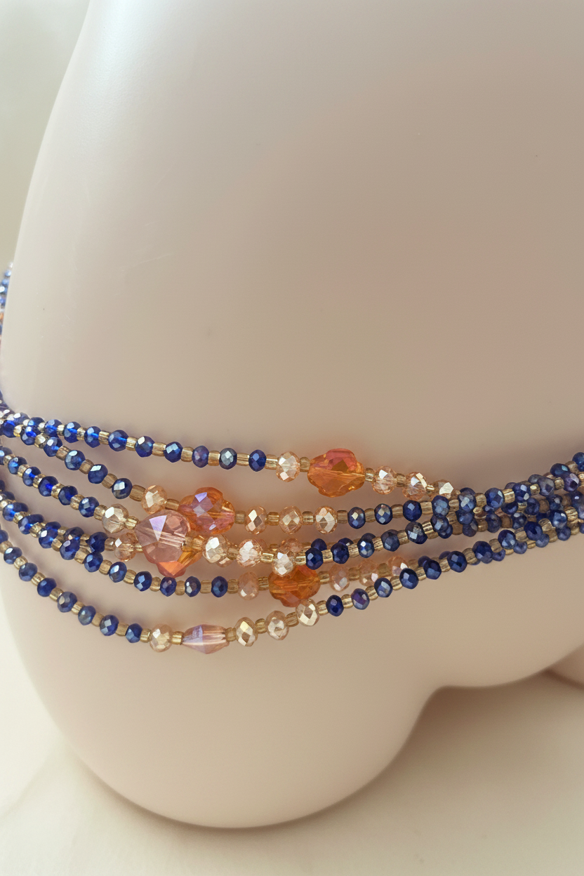 Close up of blue and orange waist beads on cream background